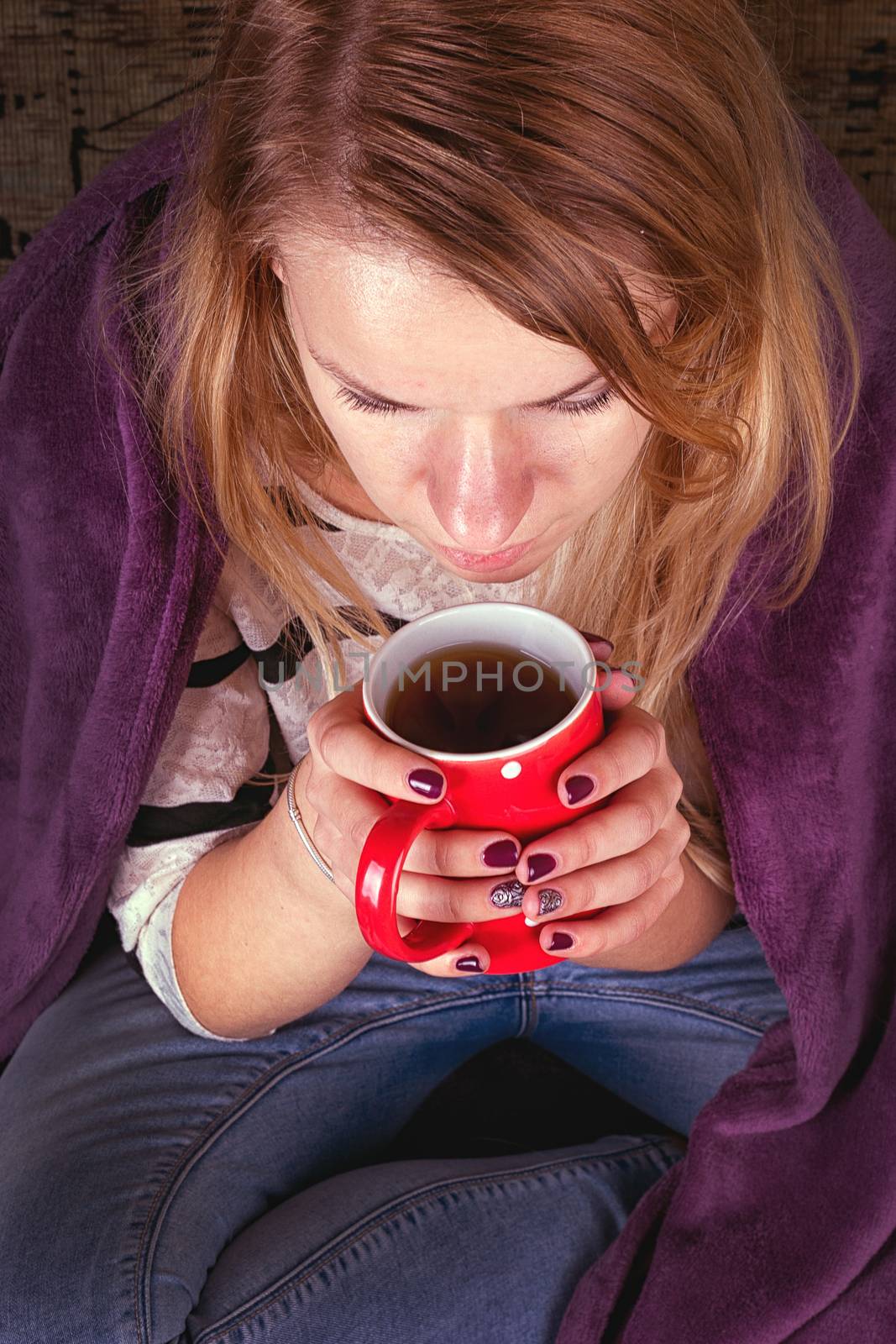 Girl sitting on sofa in livingroom with cup of tea