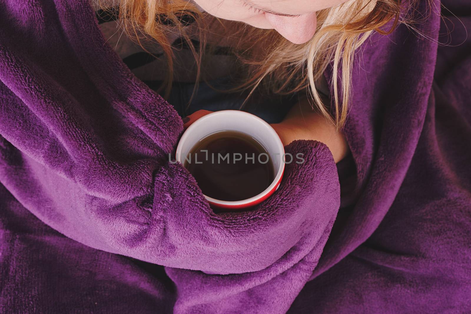 Girl sitting on sofa in livingroom with cup of tea