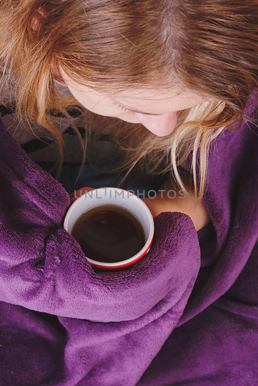 Girl sitting on sofa in livingroom with cup of tea