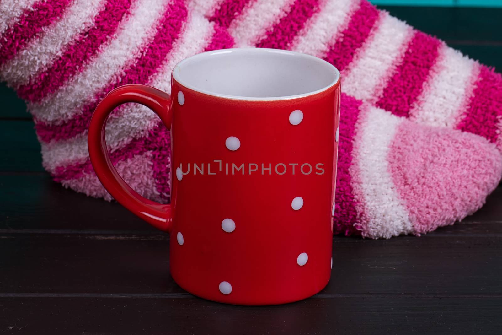 Comfort Concept - Woman drinking hot cocoa. Close-up of female legs in bright colored warm socks