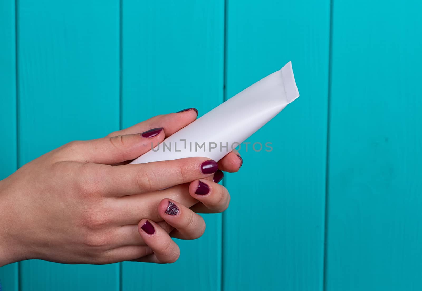 Woman's beautiful hands with care cream tube on the blue background