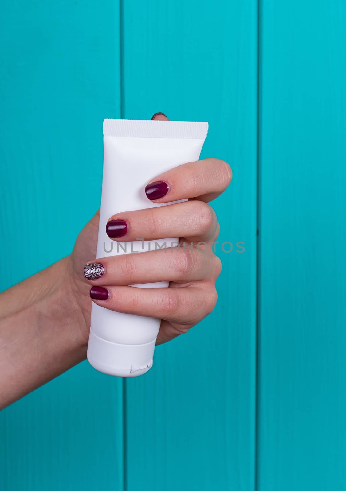 Woman's beautiful hands with care cream tube on the blue background