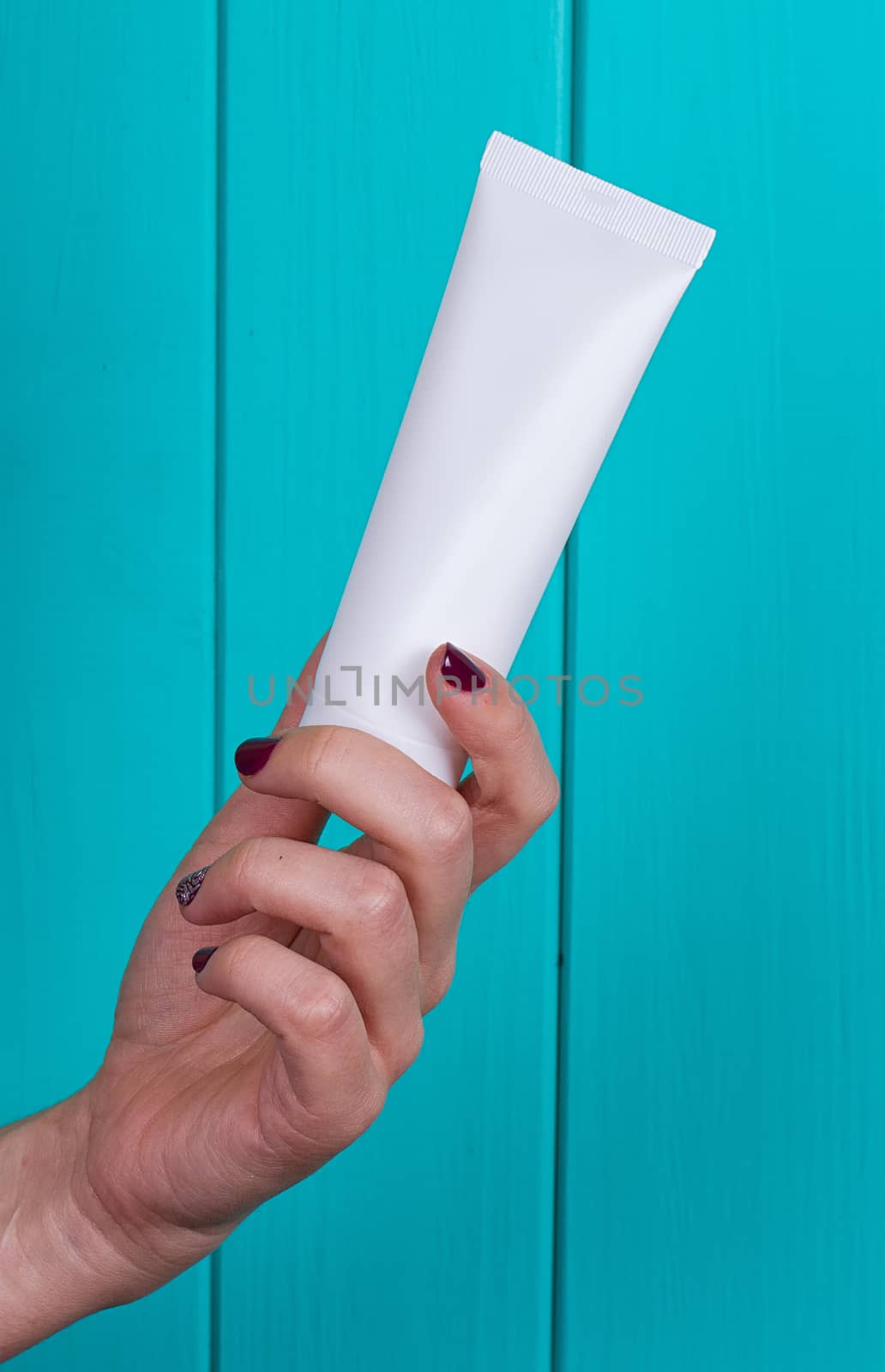 Woman's beautiful hands with care cream tube on the blue background