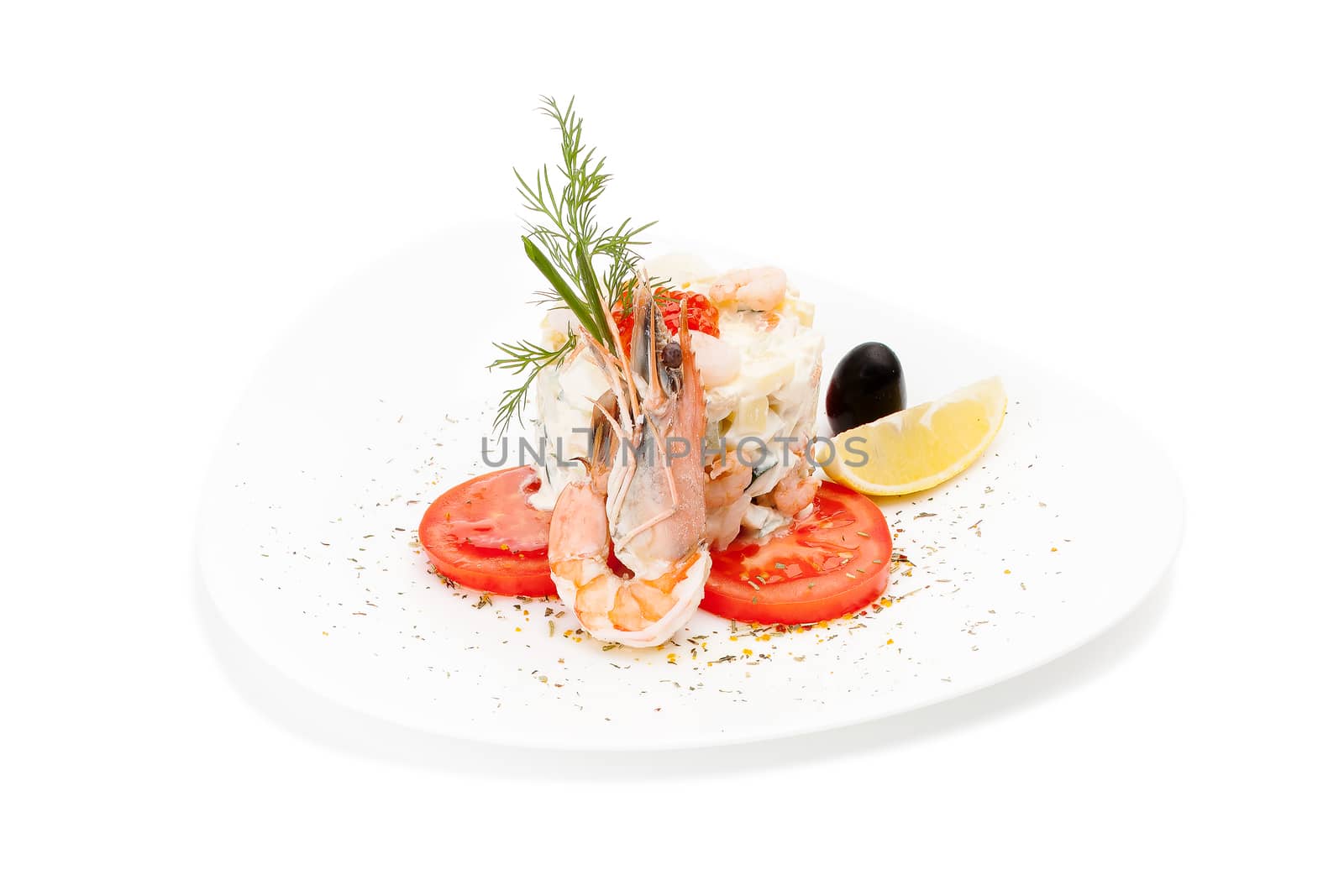 Seafood dish with shrimps. Isolated Delicious Salad with shrimps, tomatoes & fennel garnished with a olives & lemon on a white plate.
