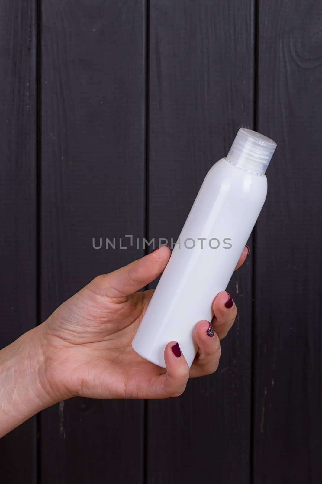 Woman's beautiful hands with care cream tube on the black background