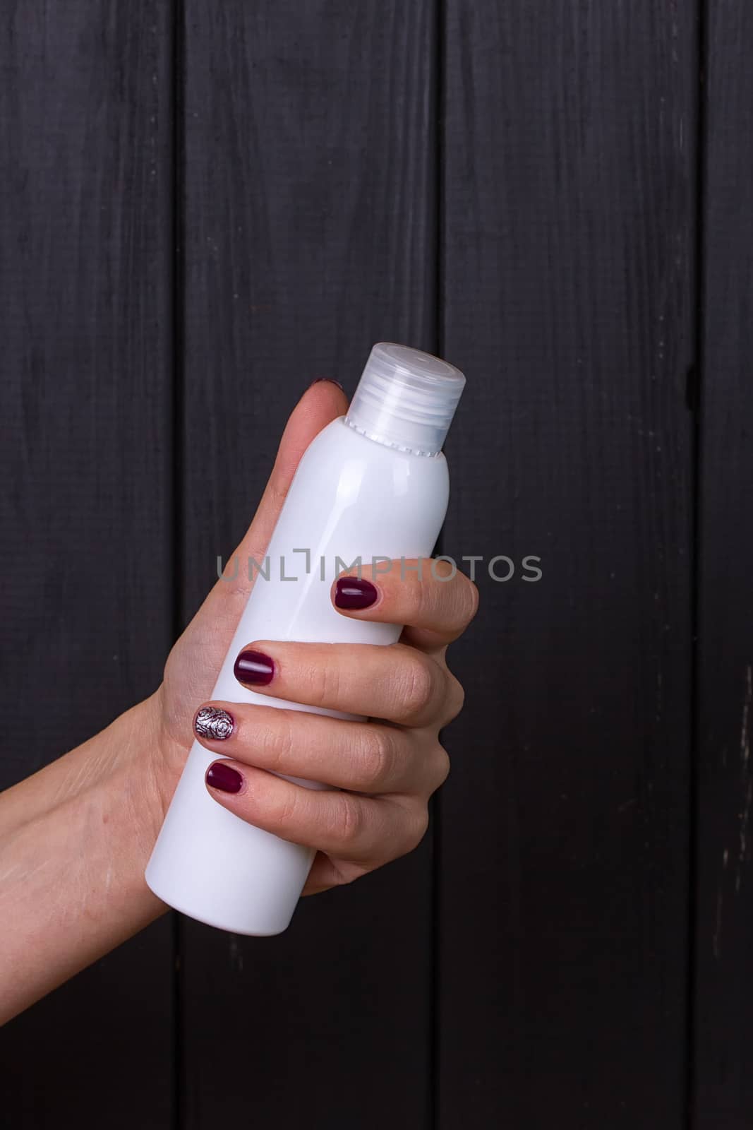 Woman's beautiful hands with care cream tube on the black background