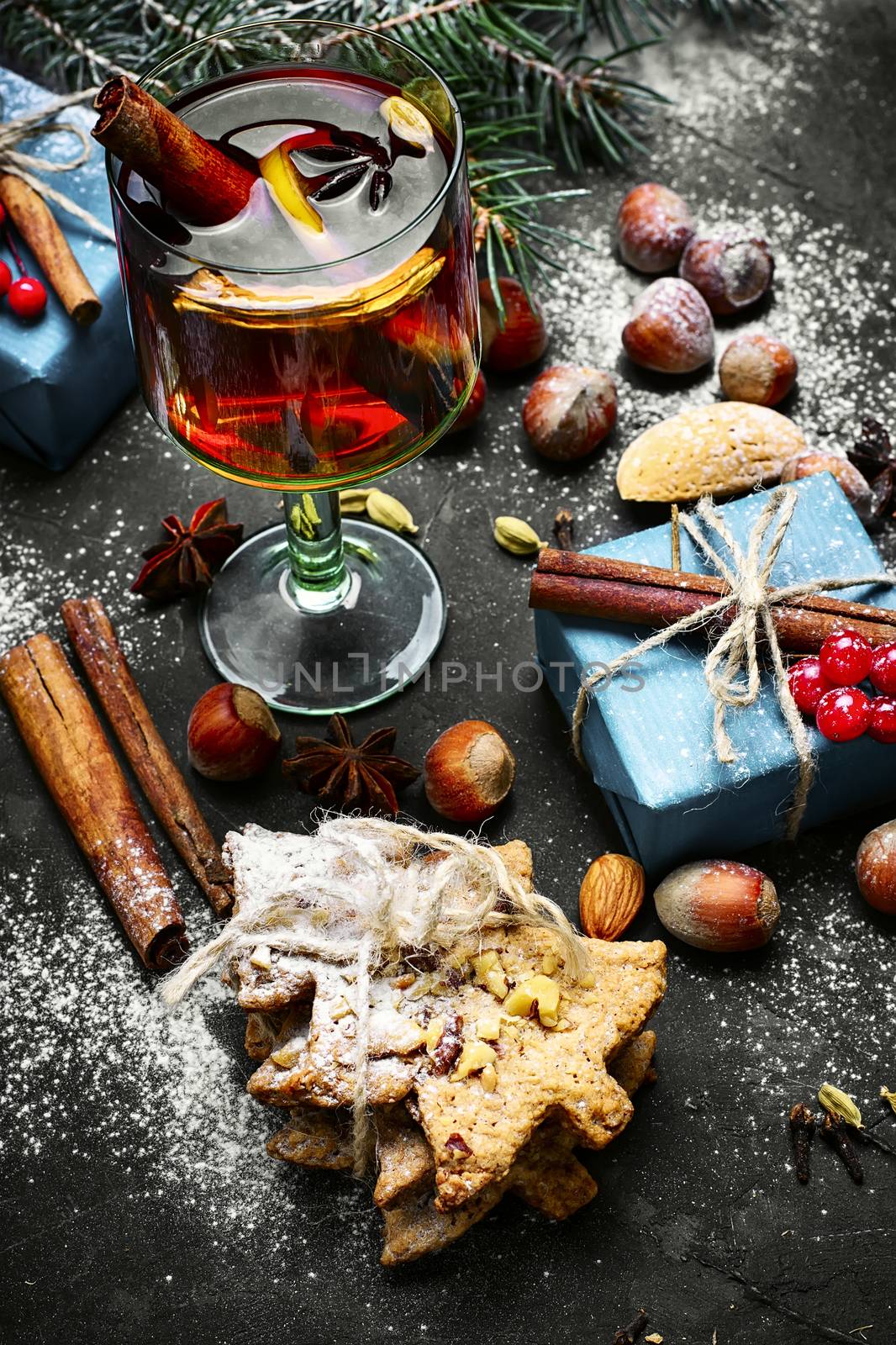glass of mulled wine on dark Christmas background with boxes of Christmas gifts and spruce branch