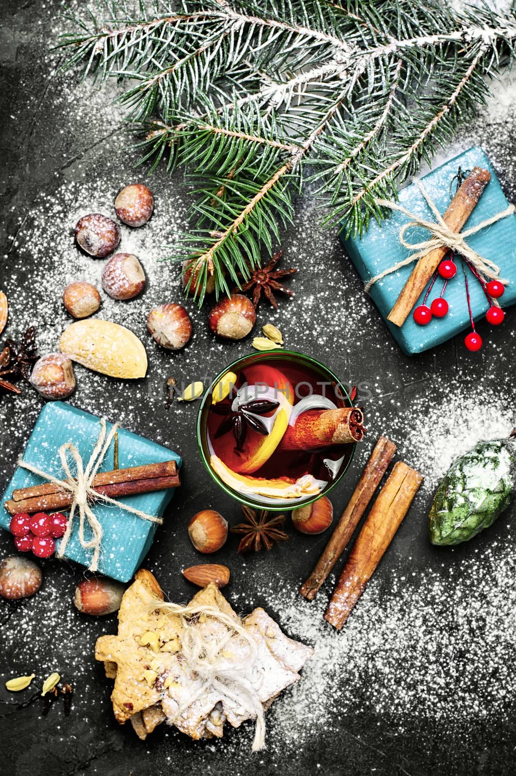 glass of mulled wine on dark Christmas background with boxes of Christmas gifts and spruce branch