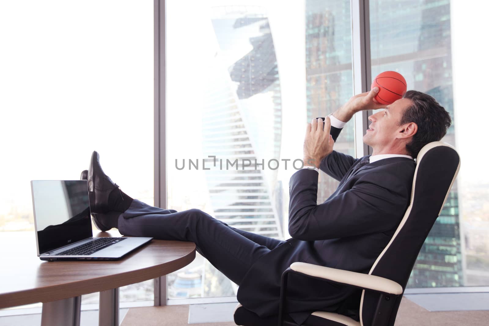 Business man playing with a basketball at the office