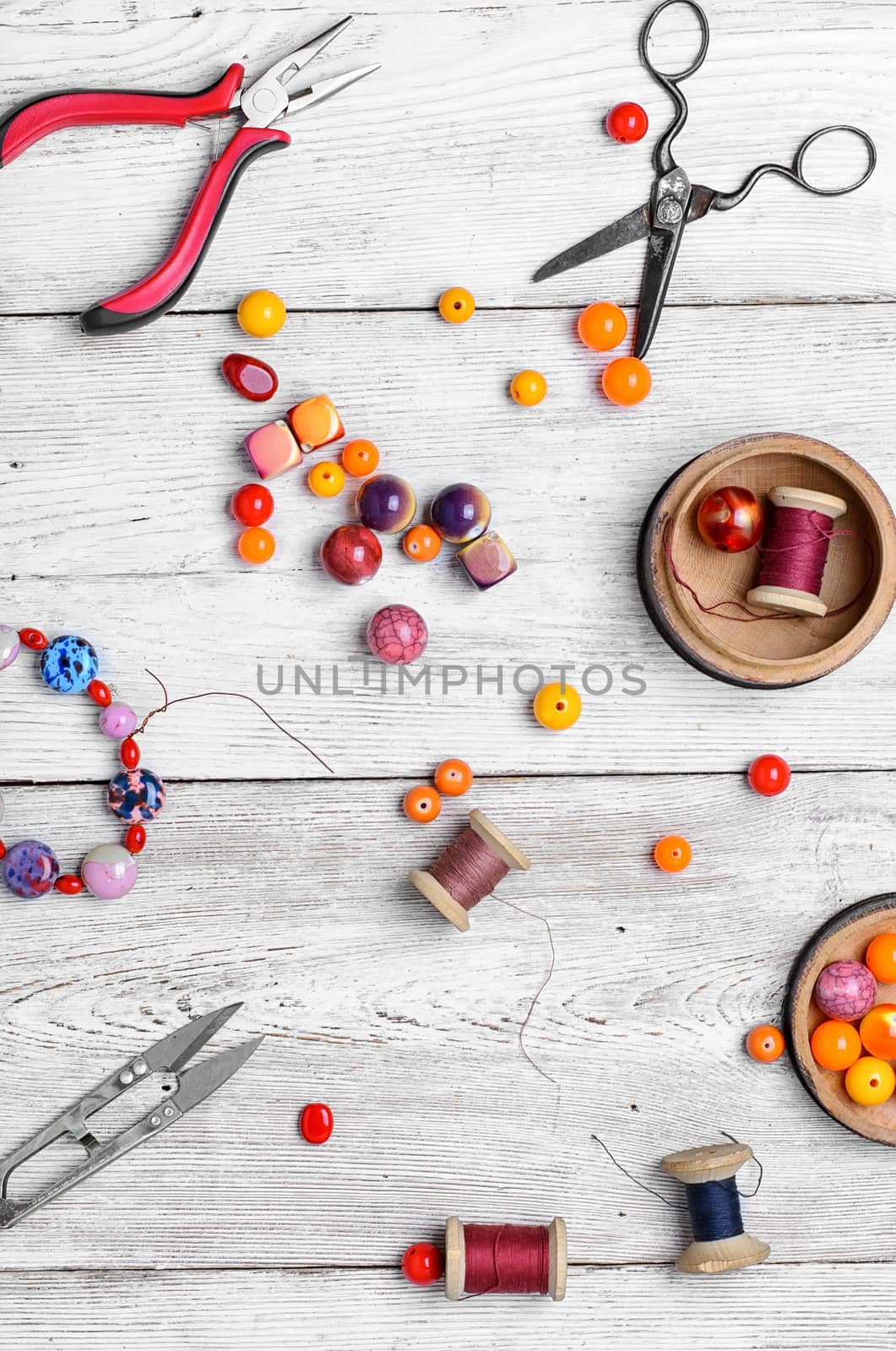 Round beads for bracelets and necklaces on white wooden background.View from the top