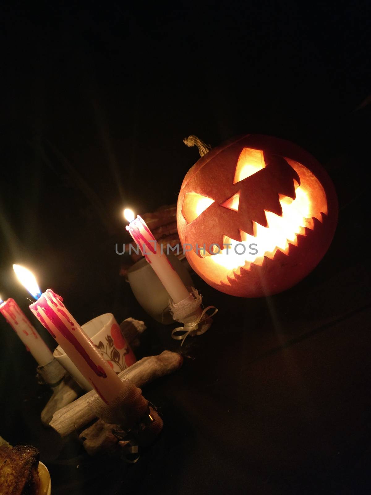 Funny Halloween pumpkin and burning candles on black background