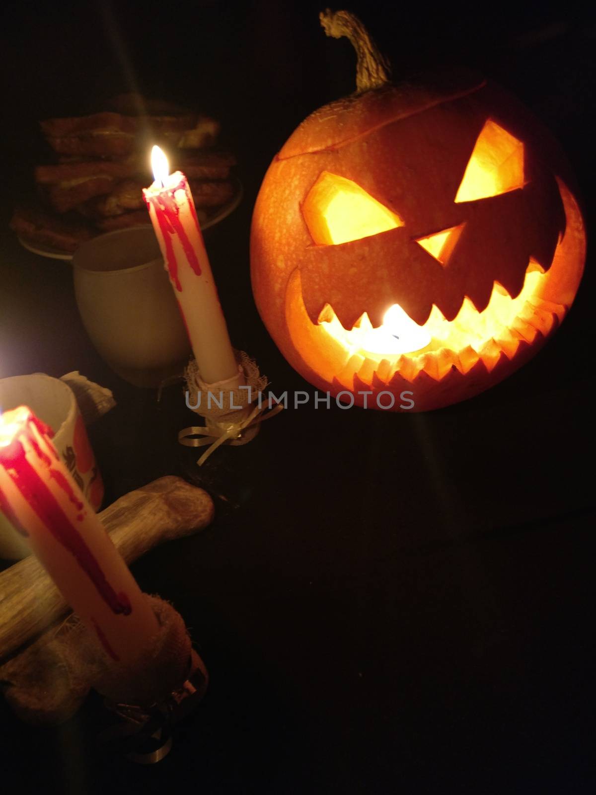 Funny Halloween pumpkin and burning candles on black background