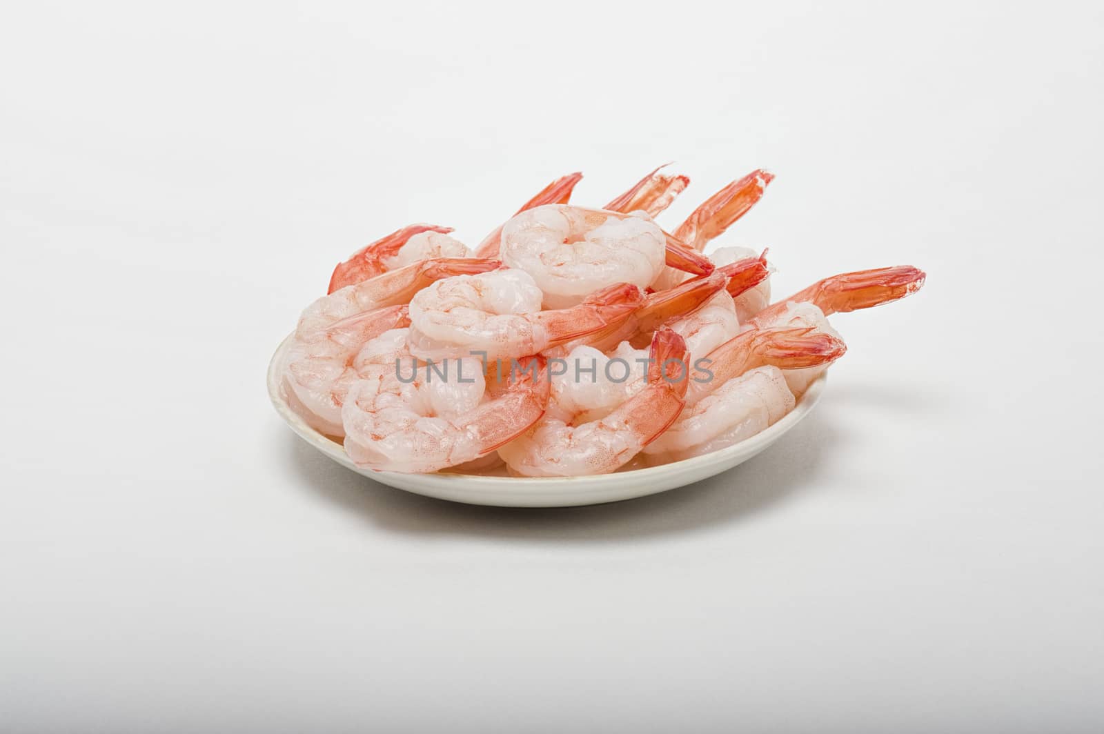 Red peeled prawns lie on a saucer isolated on white background
