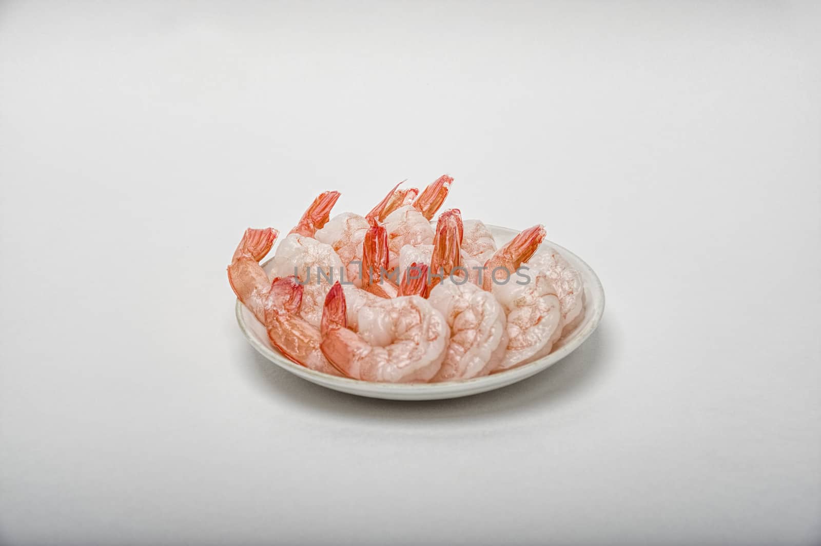Red peeled prawns lie on a saucer isolated on white background