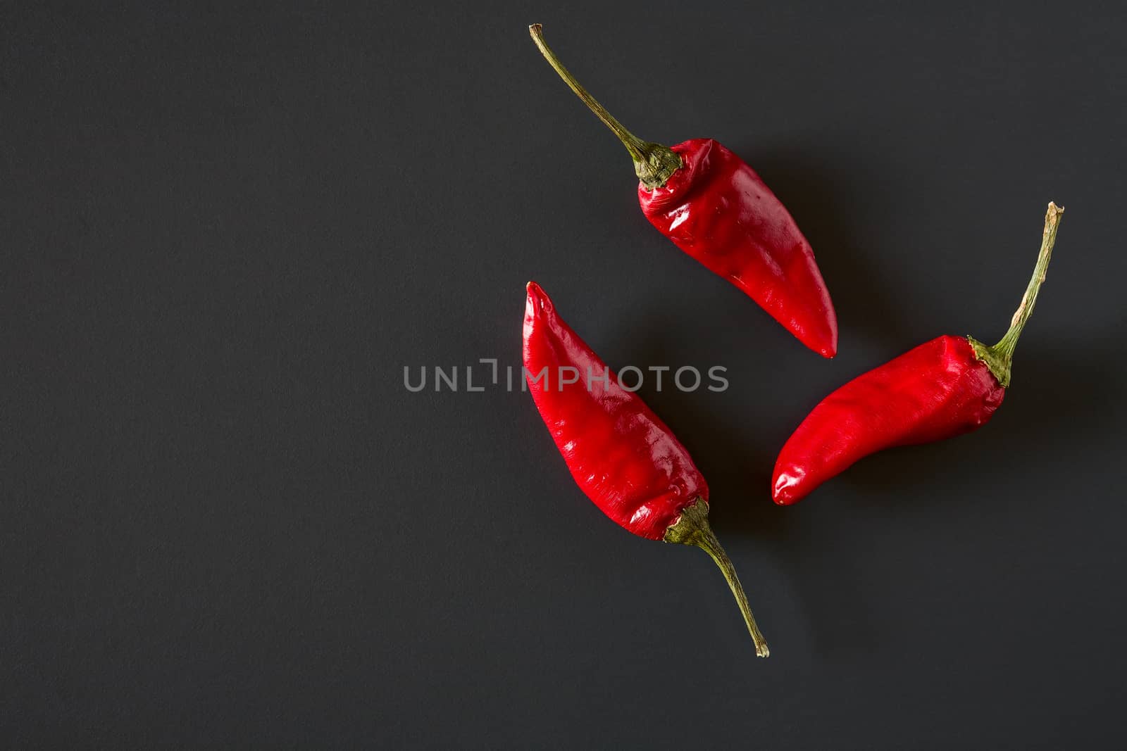 Red hot chili peppers over a dark background seen from above