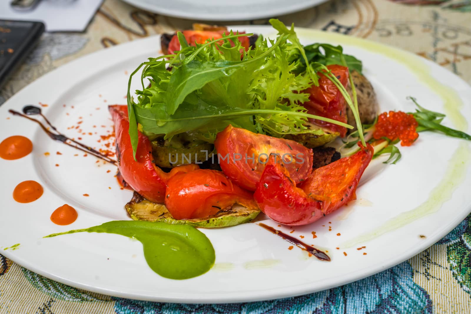 Baked tomatoes and peppers with Greens on a white plate