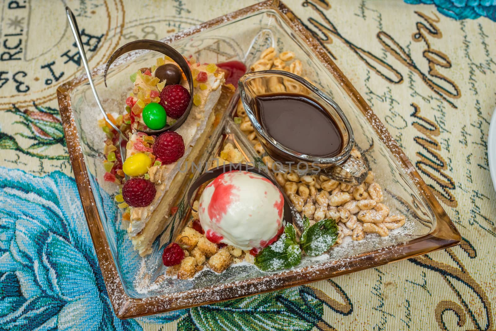 Dessert with ice cream, raspberries and melted chocolate on a white plate