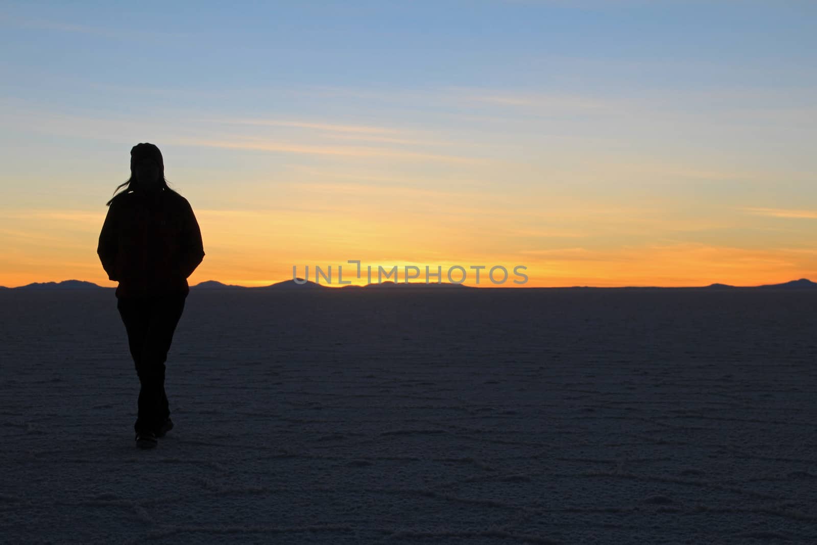 Woman walking on Salar de Uyuni, salt lake, is largest salt flat in the world, altiplano, Bolivia, South America