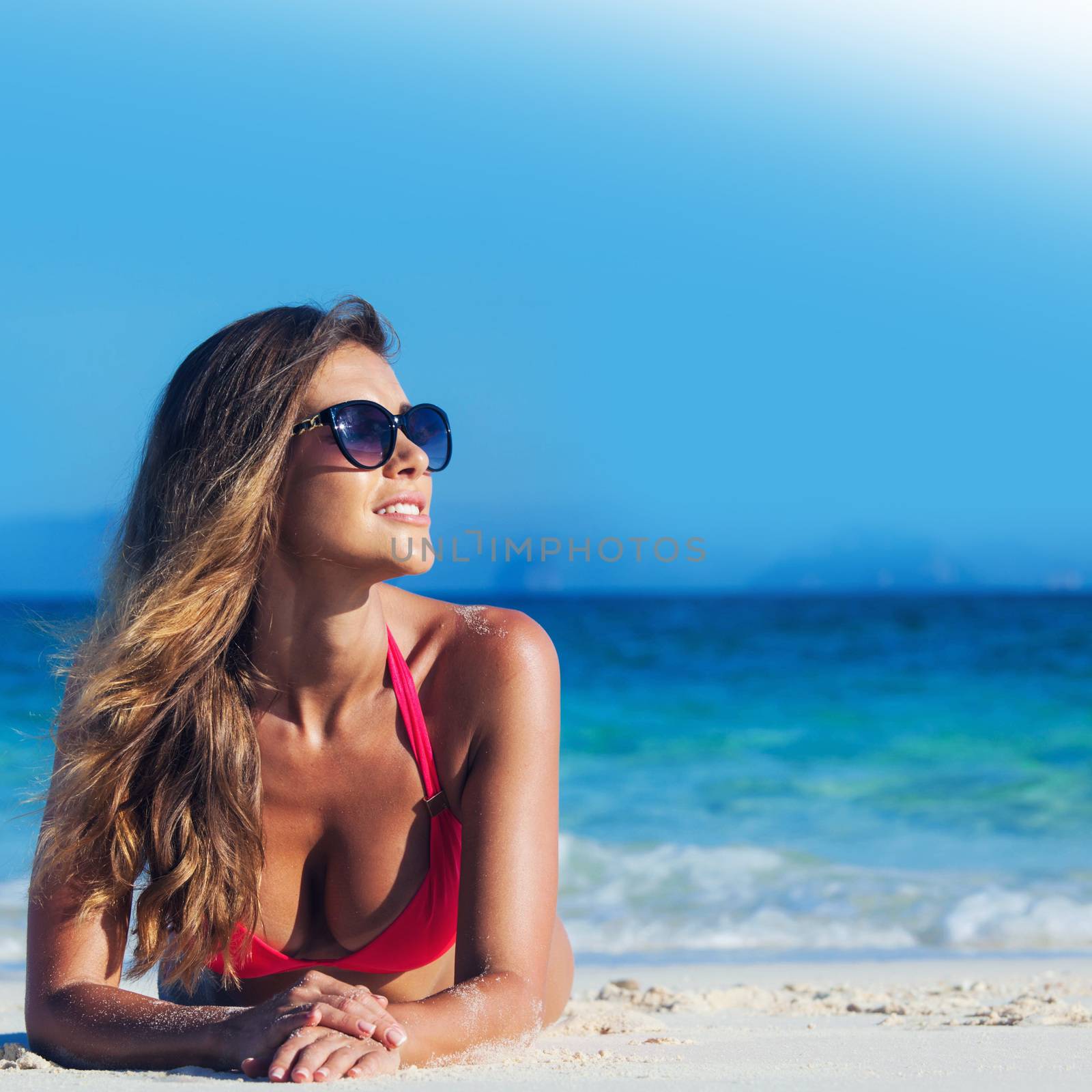 Young woman in bikini laying by tropical sea