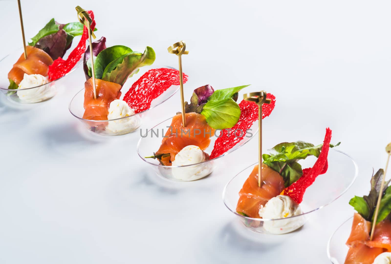 Salmon snack with soft cheese, fresh salad and basil on light background