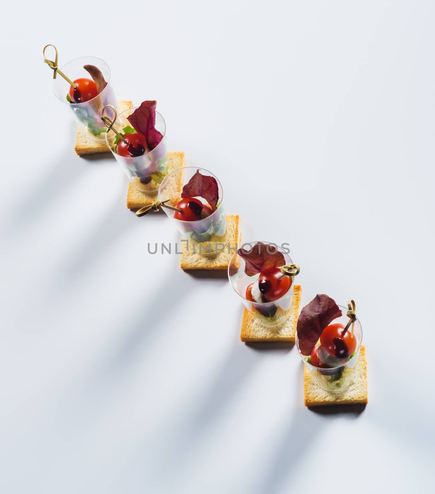 Canape with cherry-tomato and soft cheese on light background