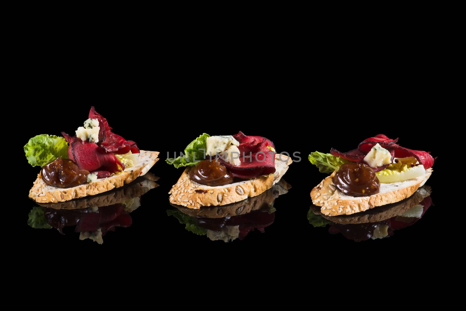 Bruschettas with beef and cheese on black background