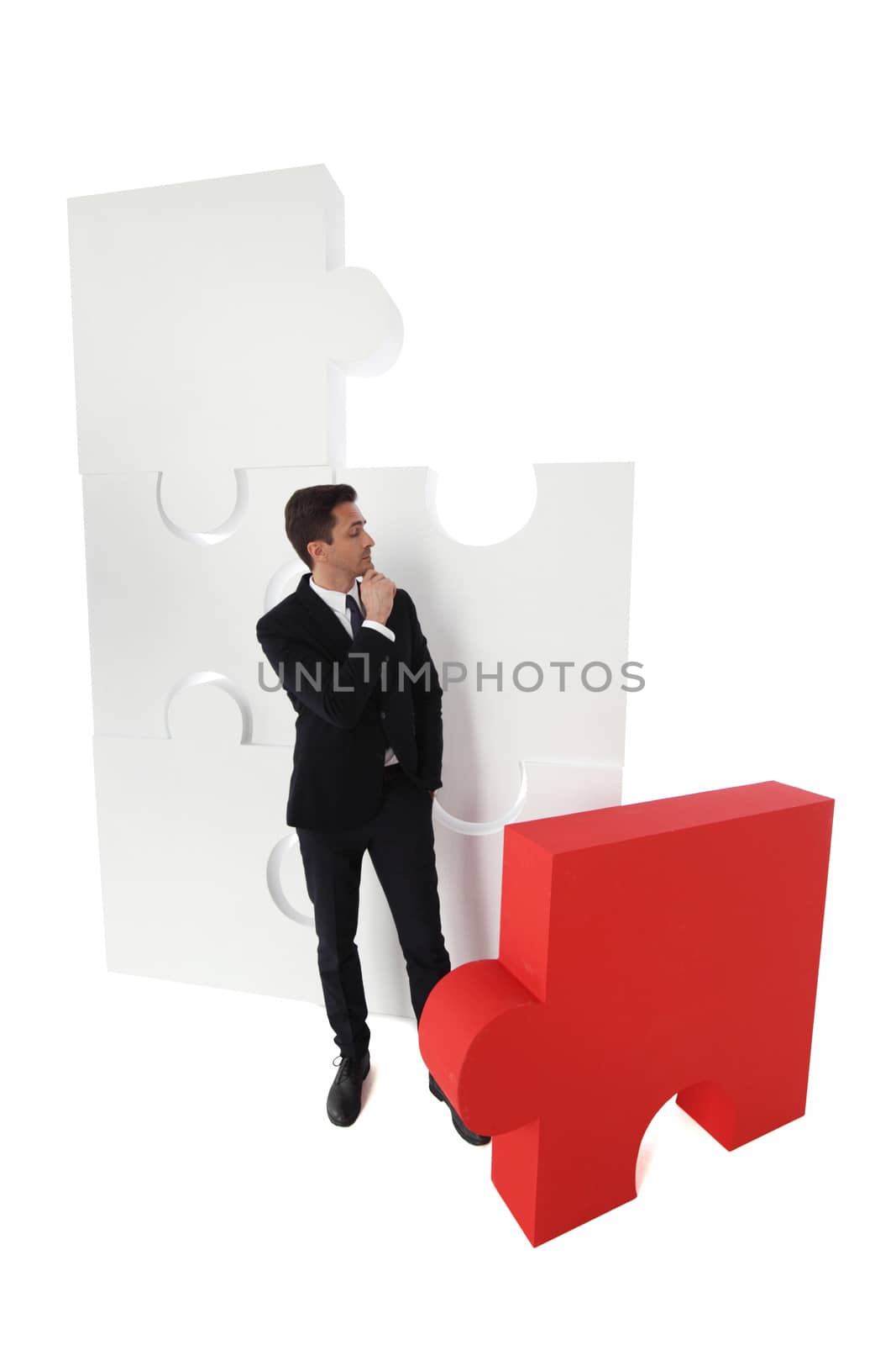 Business man thinking about assembling jigsaw puzzle isolated on white background