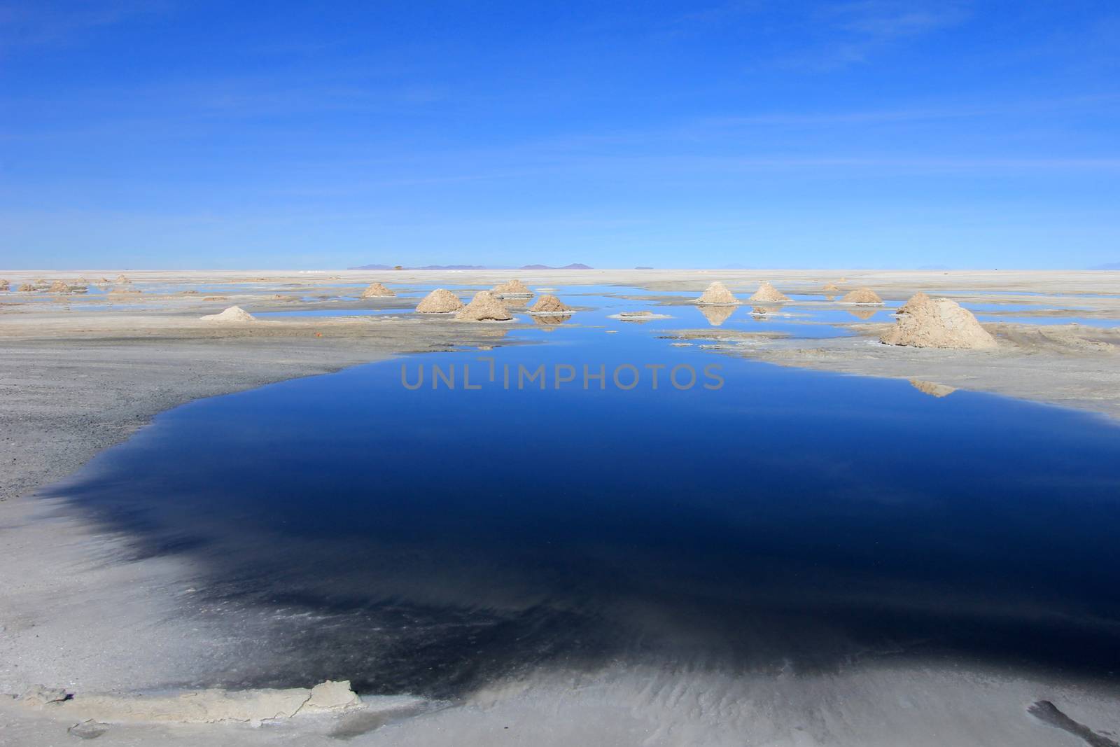 Hills of salt behind lake, salt extraction area at the world's biggest salt lake, Salar de Uyuni, Bolivia