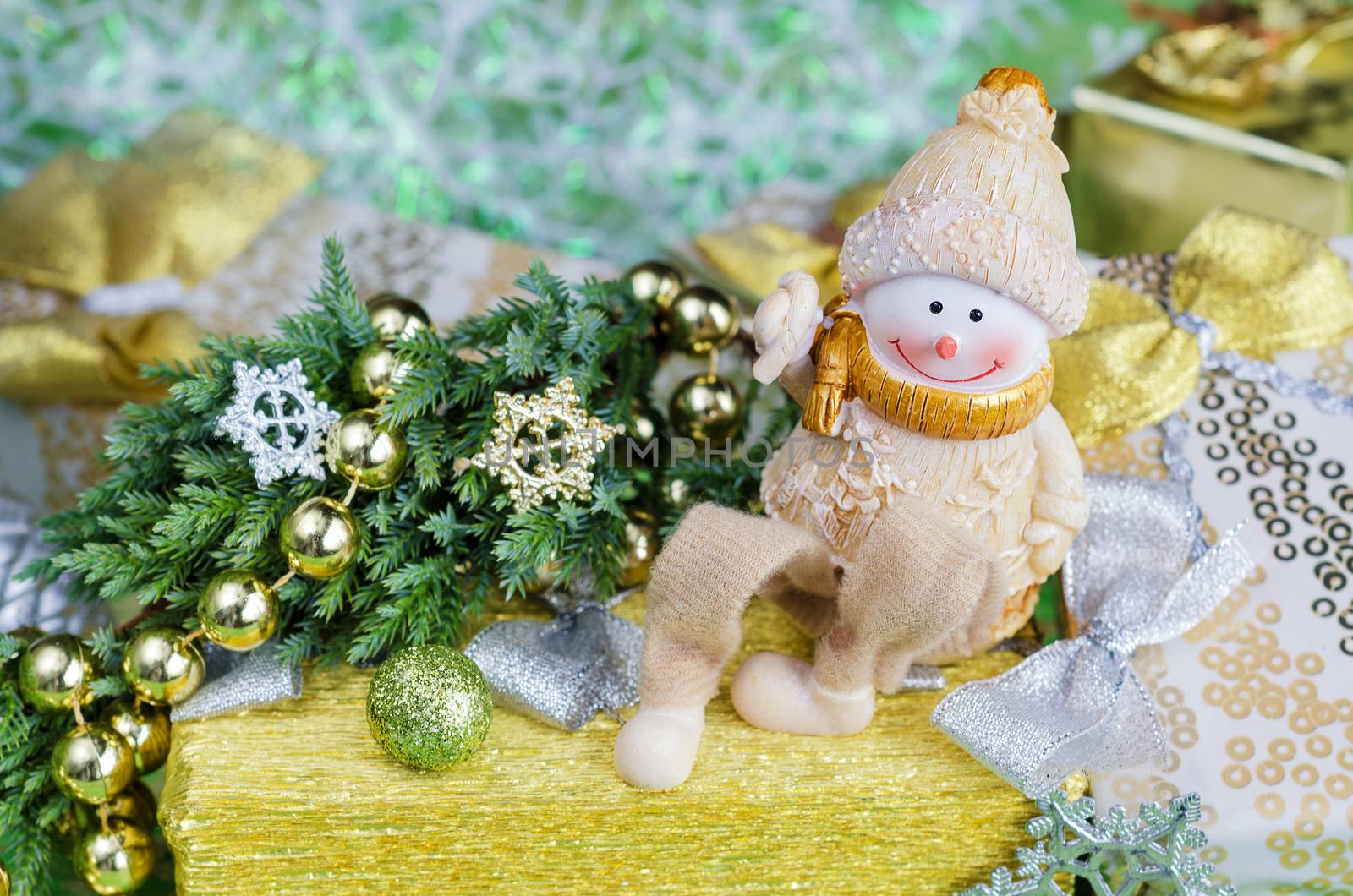 Christmas arrangement in green and gold tones. Cheerful Snowman, gifts and Christmas decorations. Selective focus.