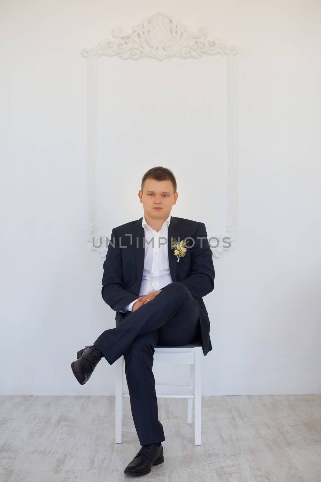 A man in a business suit sitting on a chair in the apartment