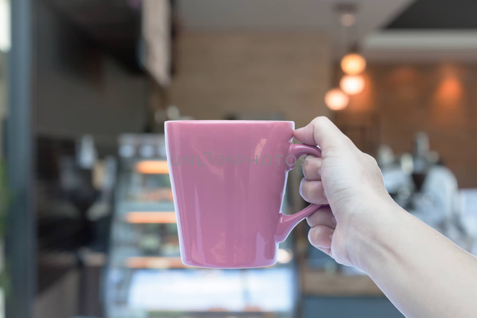 Woman hands holding coffee cup with blurred coffee shop by punsayaporn