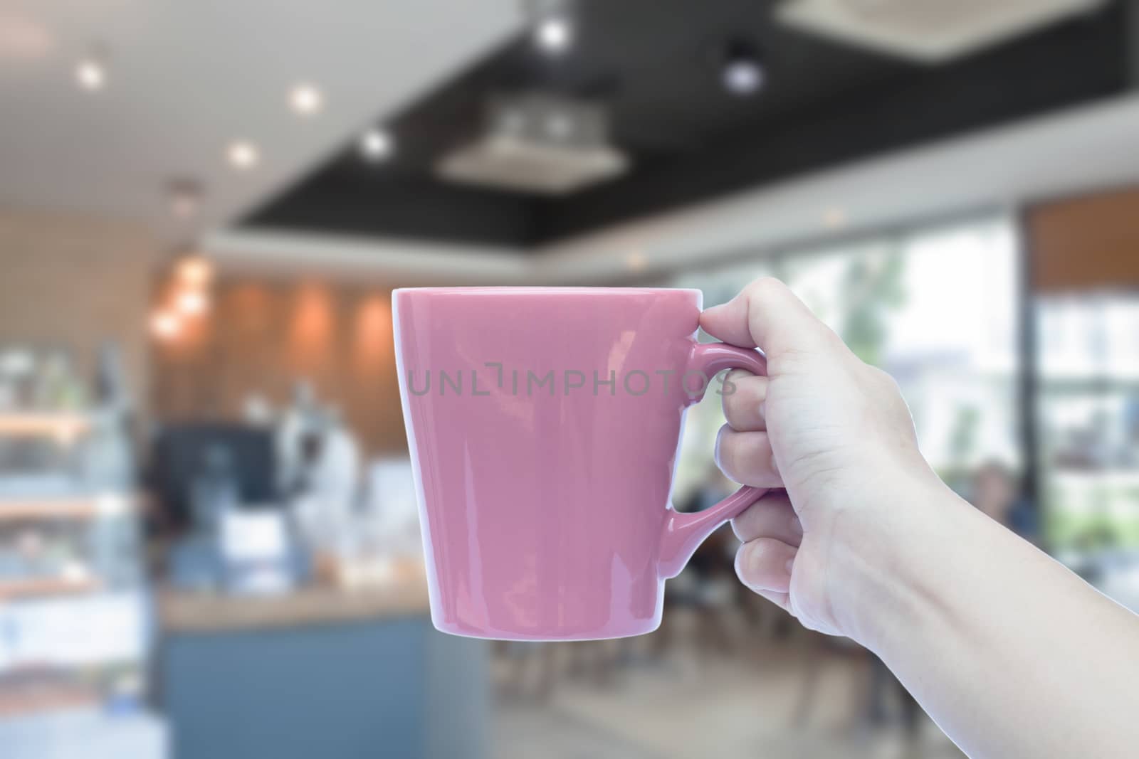 Women hand holding mug with blurred cafe  by punsayaporn