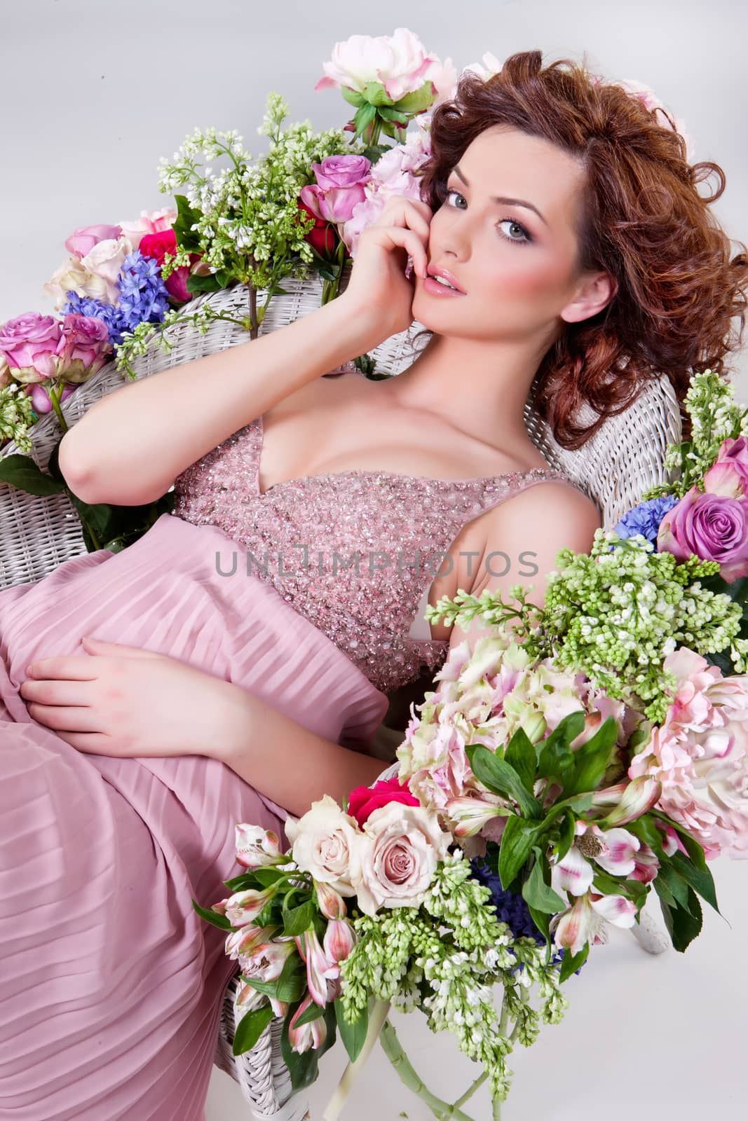 Young beautiful woman sitting in armchair with different flowers