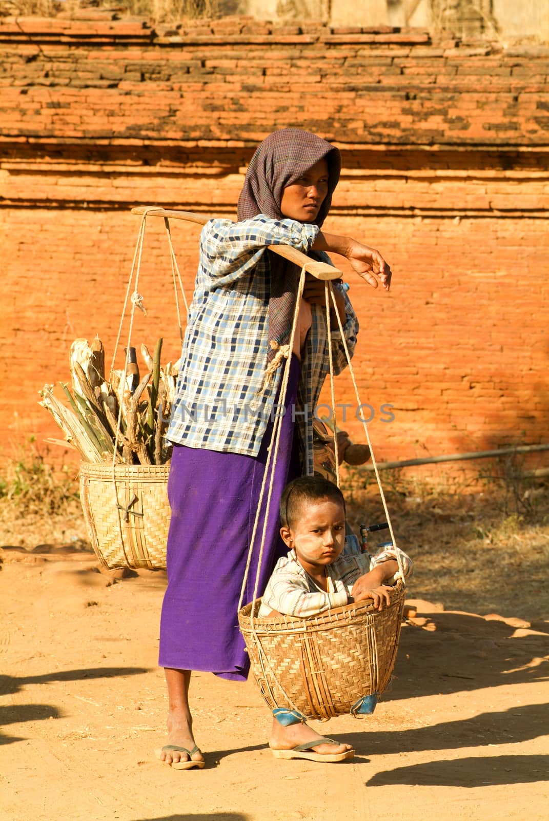 Bagan, Myanmar - 24 January 2010: Woman with her son on a basket at the archaeological site of Bagan on Myanmar
