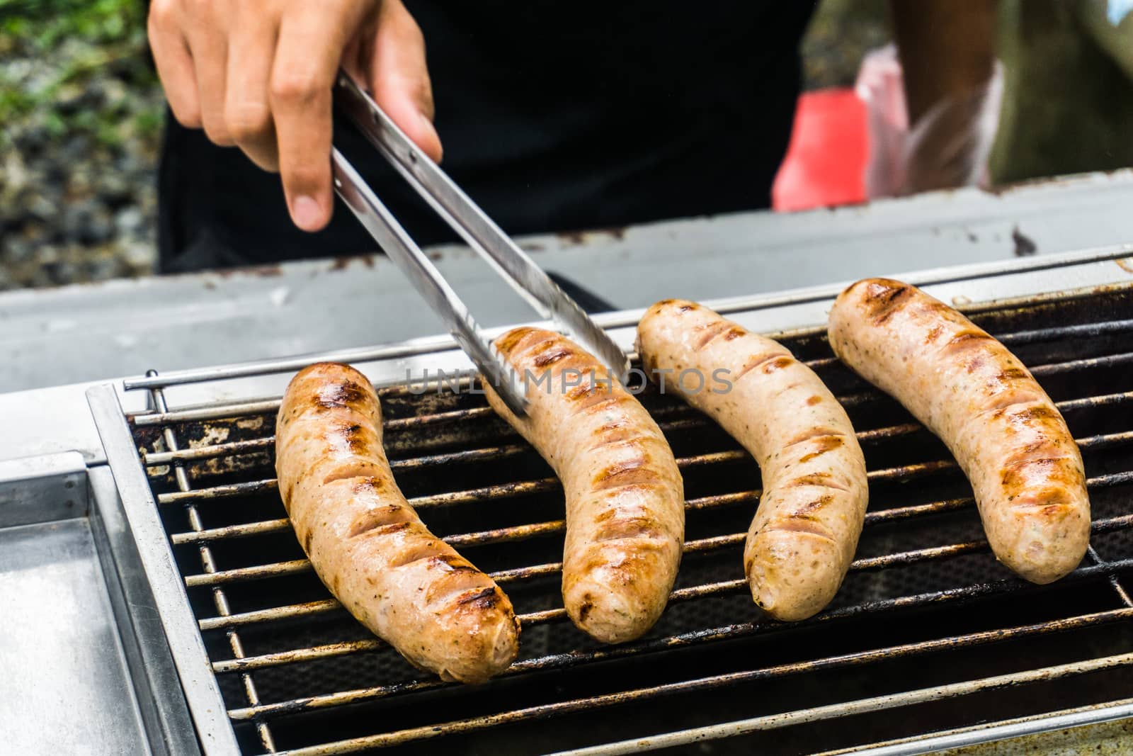 Fresh sausage and hot dogs grilling outdoors on a gas barbecue g by nopparats