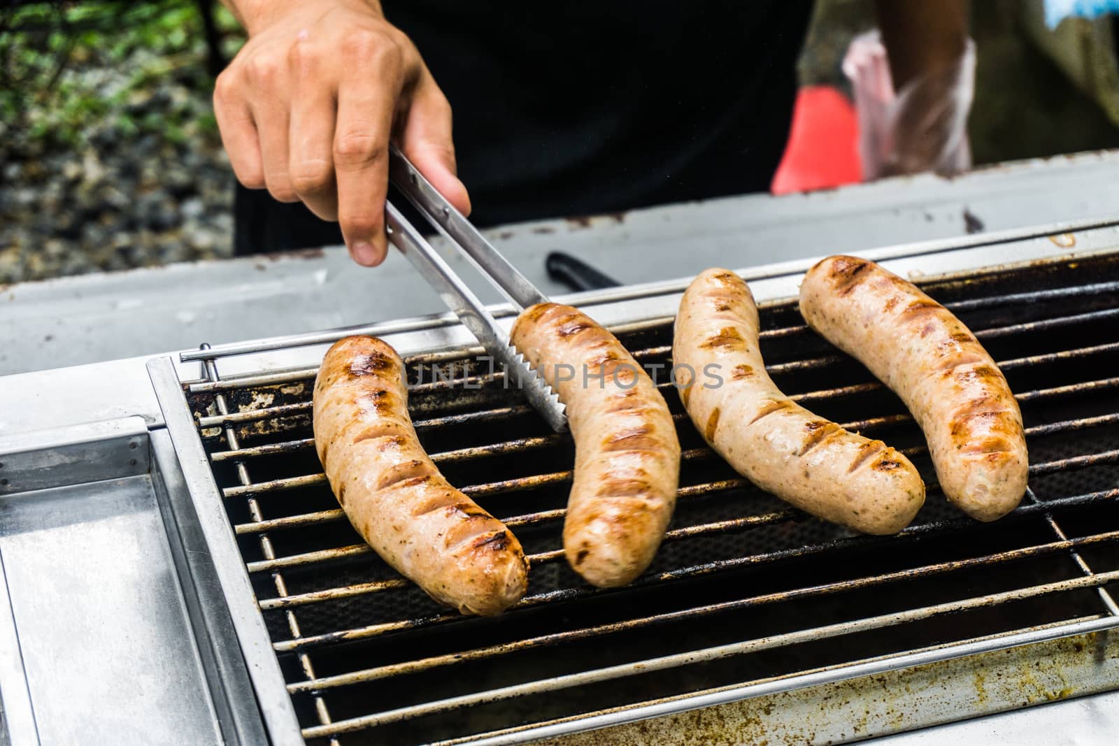 Fresh sausage and hot dogs grilling outdoors on a gas barbecue g by nopparats