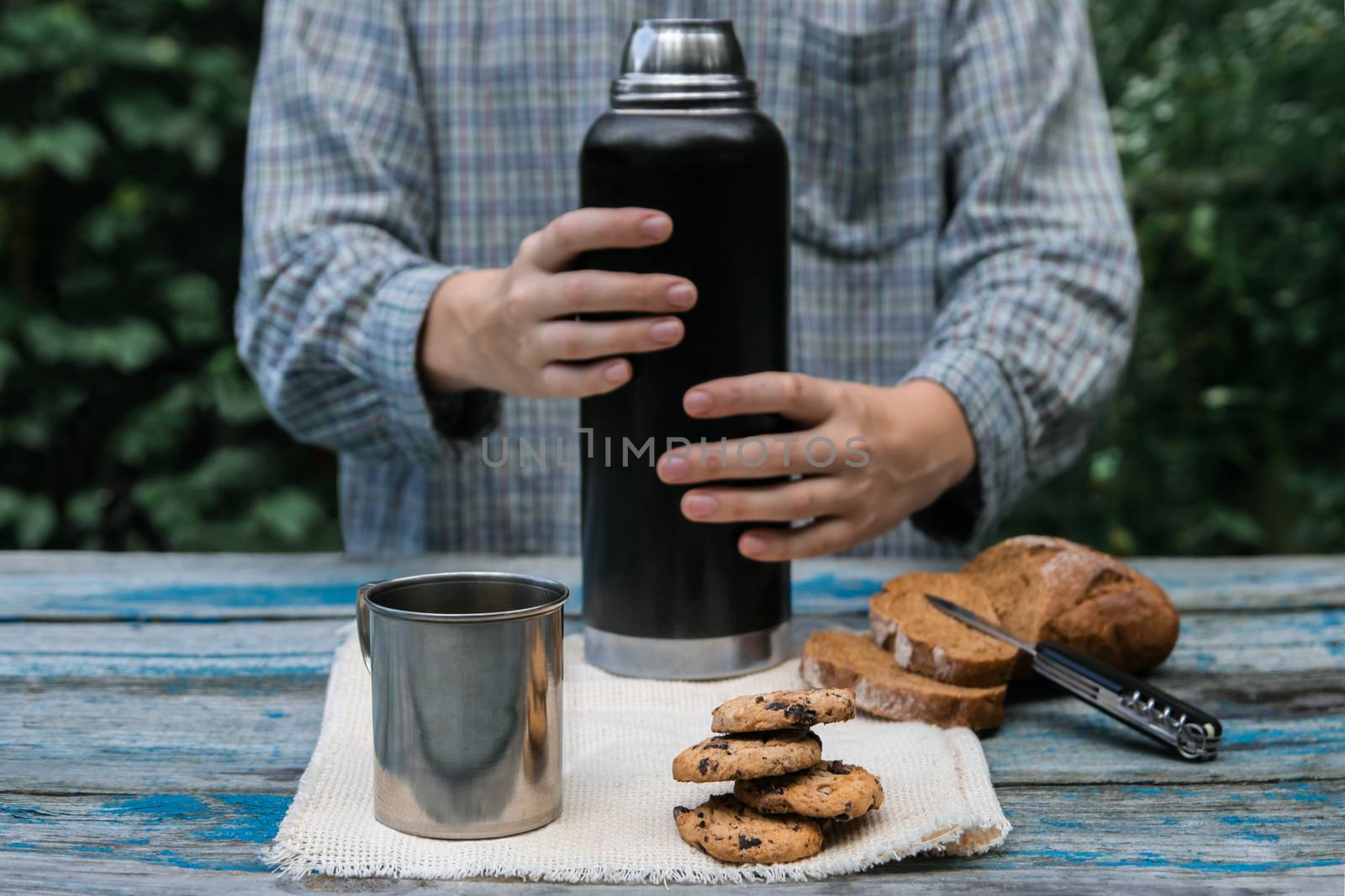 Thermos, cookies, metal cup, bread slices on wooden table by photoboyko