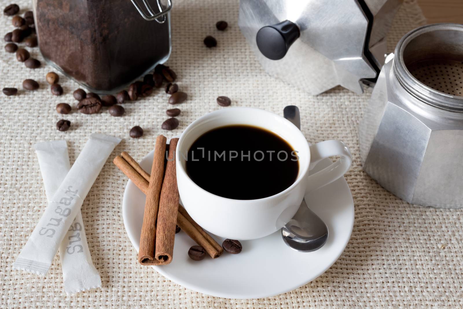 Cup of black coffee with italian coffee pot on flax fabric, top view