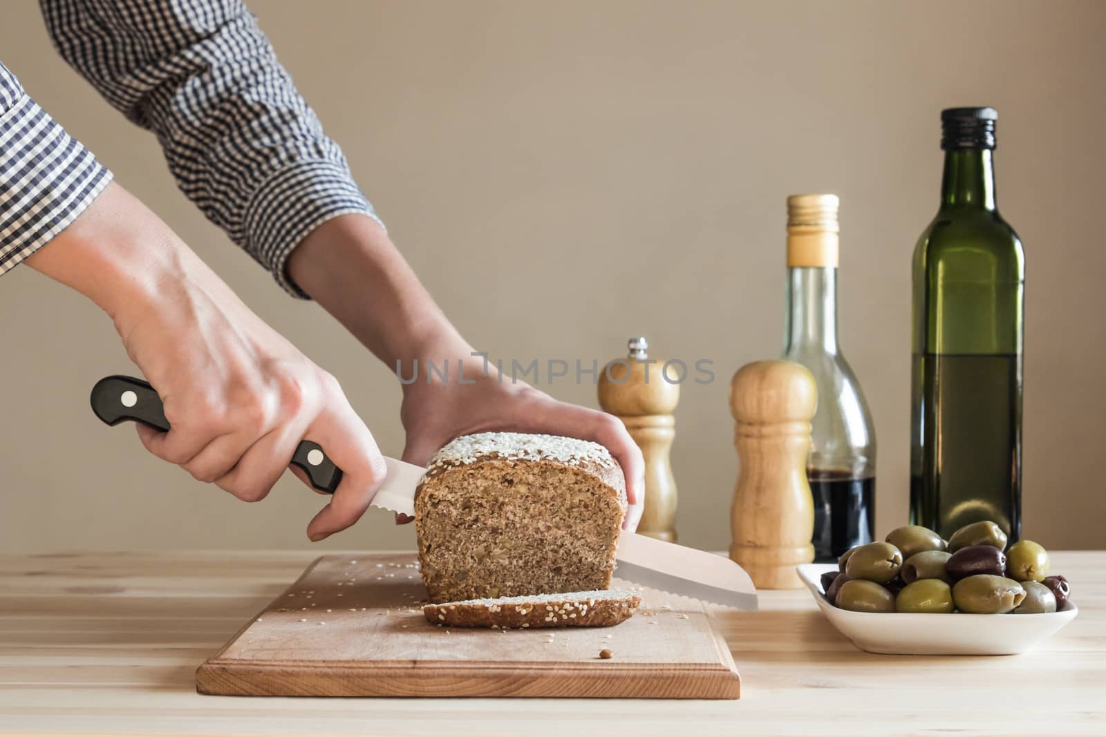 Bread cut by female hands in the kitchen by photoboyko