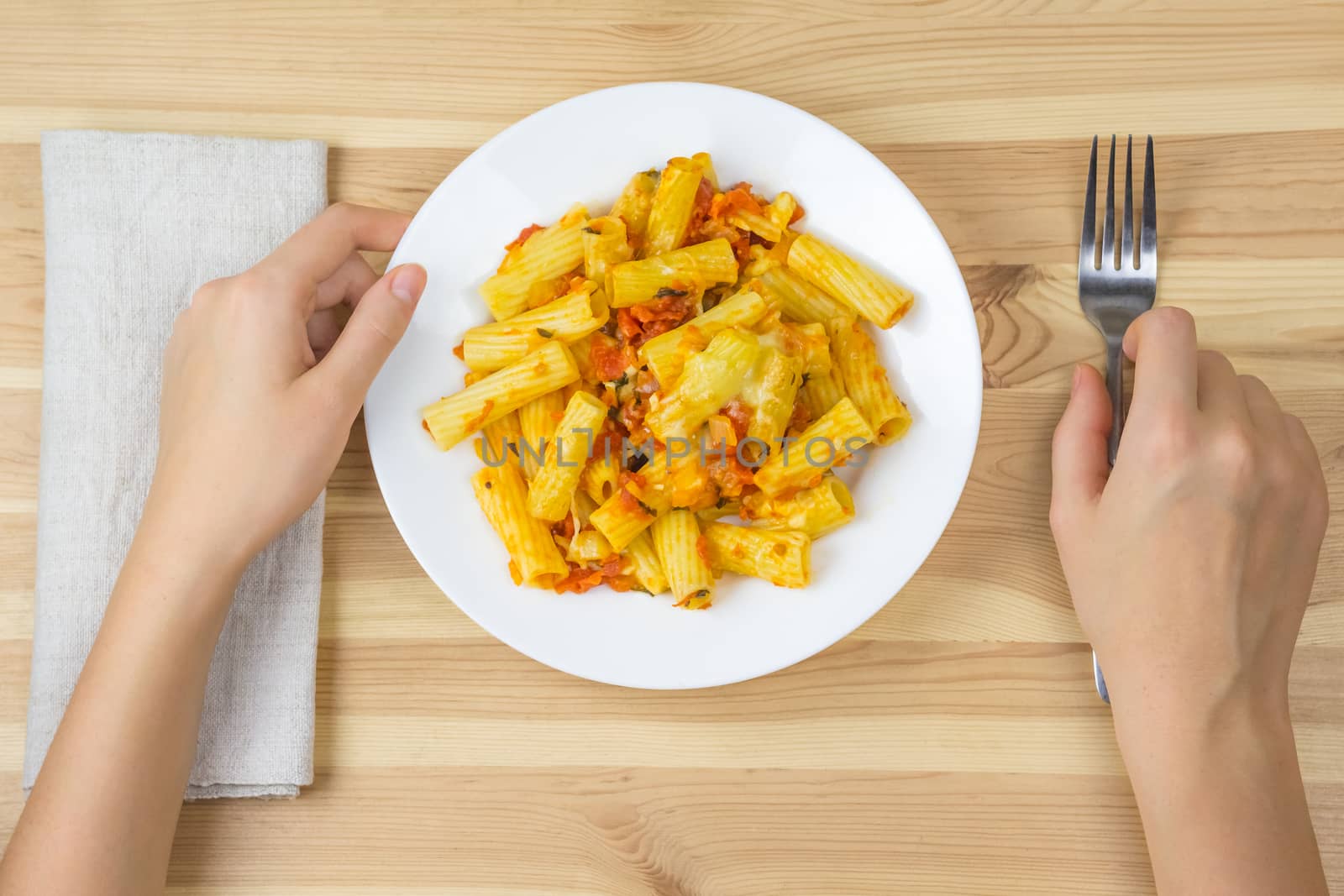 baked tortiglioni pasta with tomato sauce, mozzarella and parmesan cheese in plate on wooden table