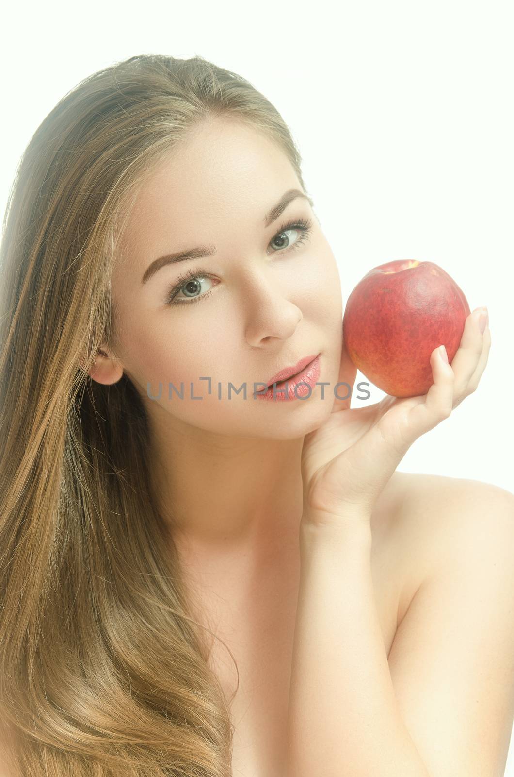 Tender young girl with a peach in her hand on a white background. Vertical photo