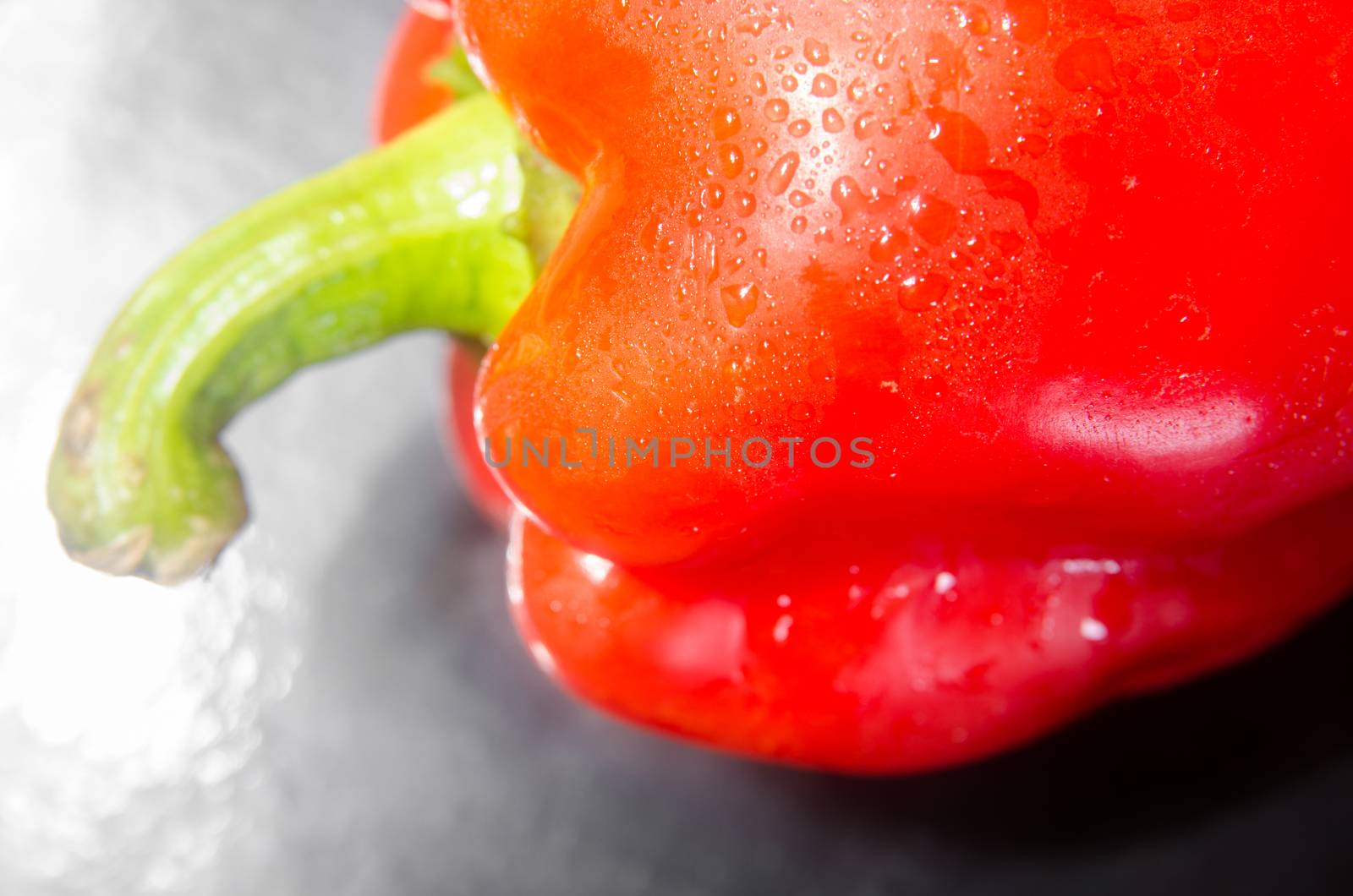 Red pepper with a green sprig on a black background. Horizontal photo. Side view