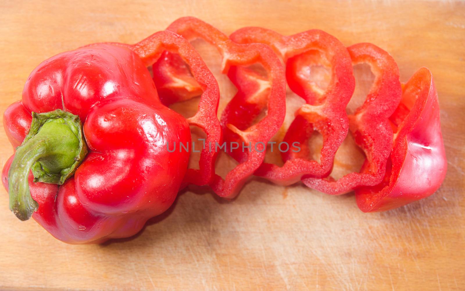 Red pepper cut by slice on a wooden background. Horizontal photo