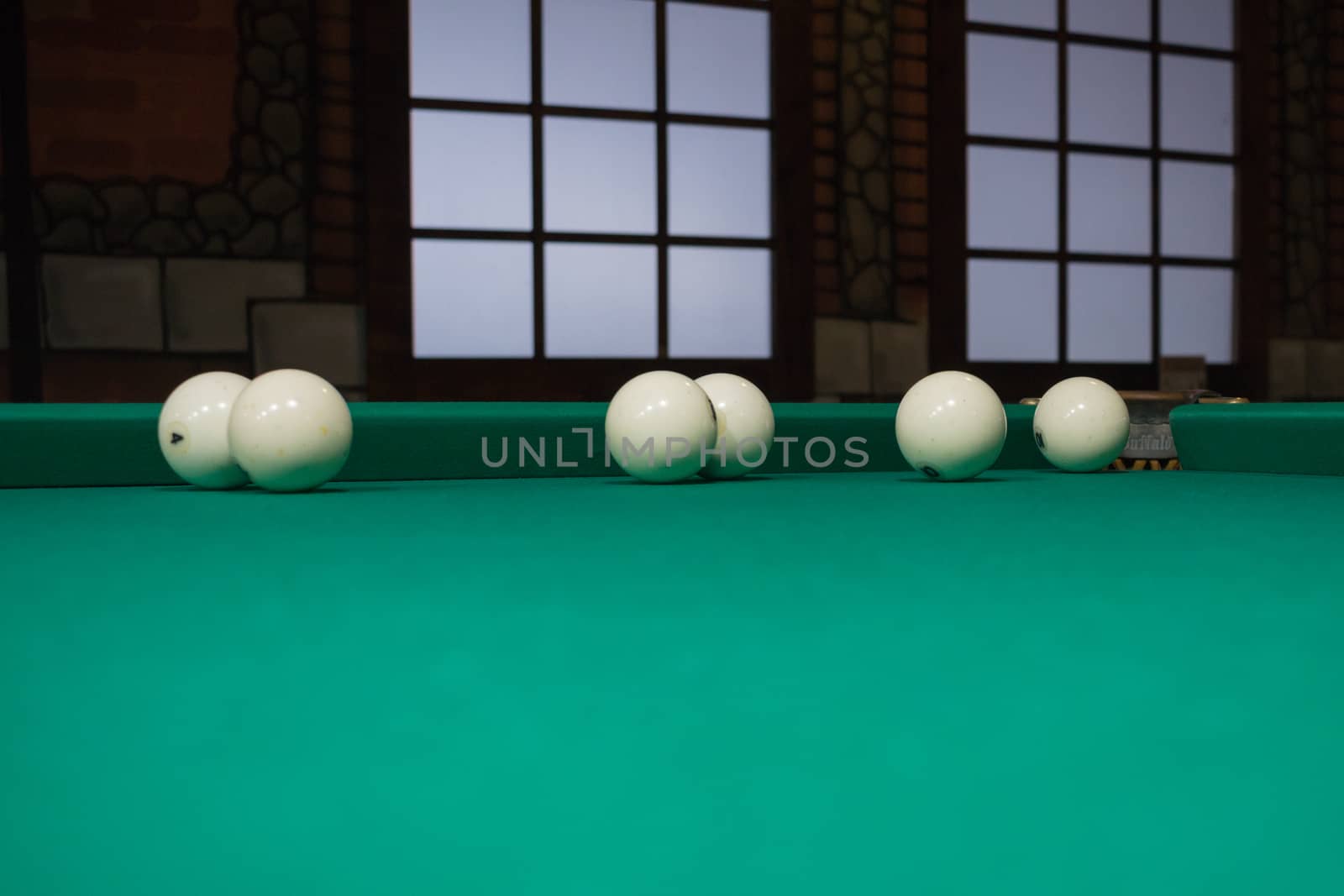Russian billiards balls on green game table cloth in the middle of game with windows on background
