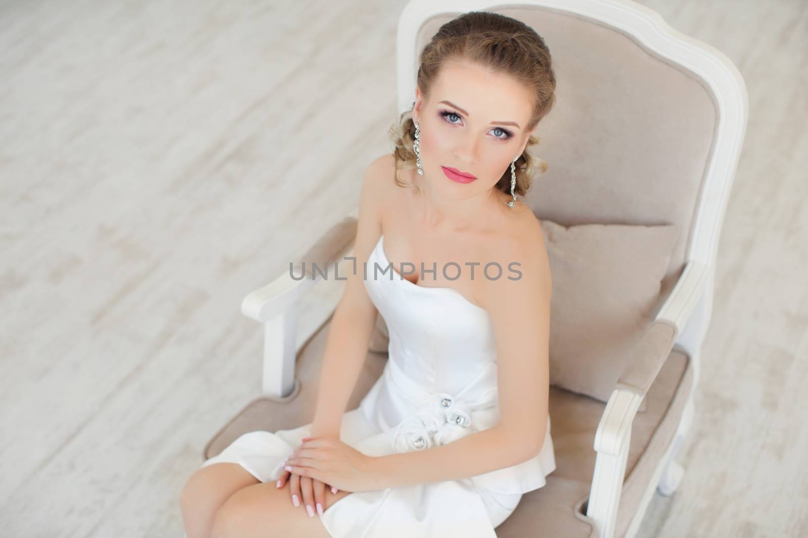 A girl sits in a chair in a white dress posing in the photo