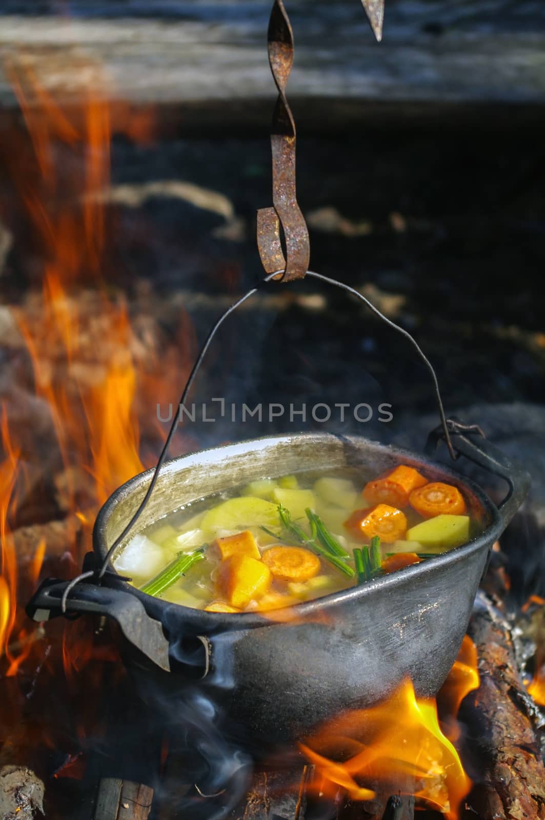 vegetable soup in old tourist pot at fire place Summer trekking activity