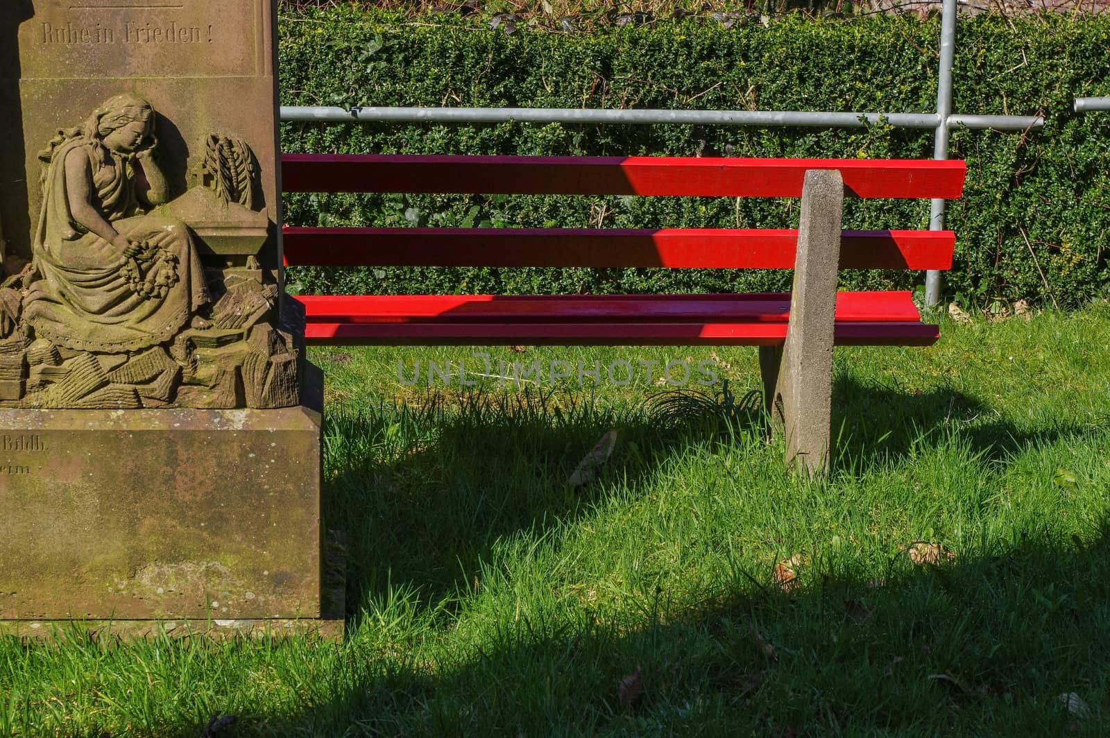 a part of wooden red park bench near a statue