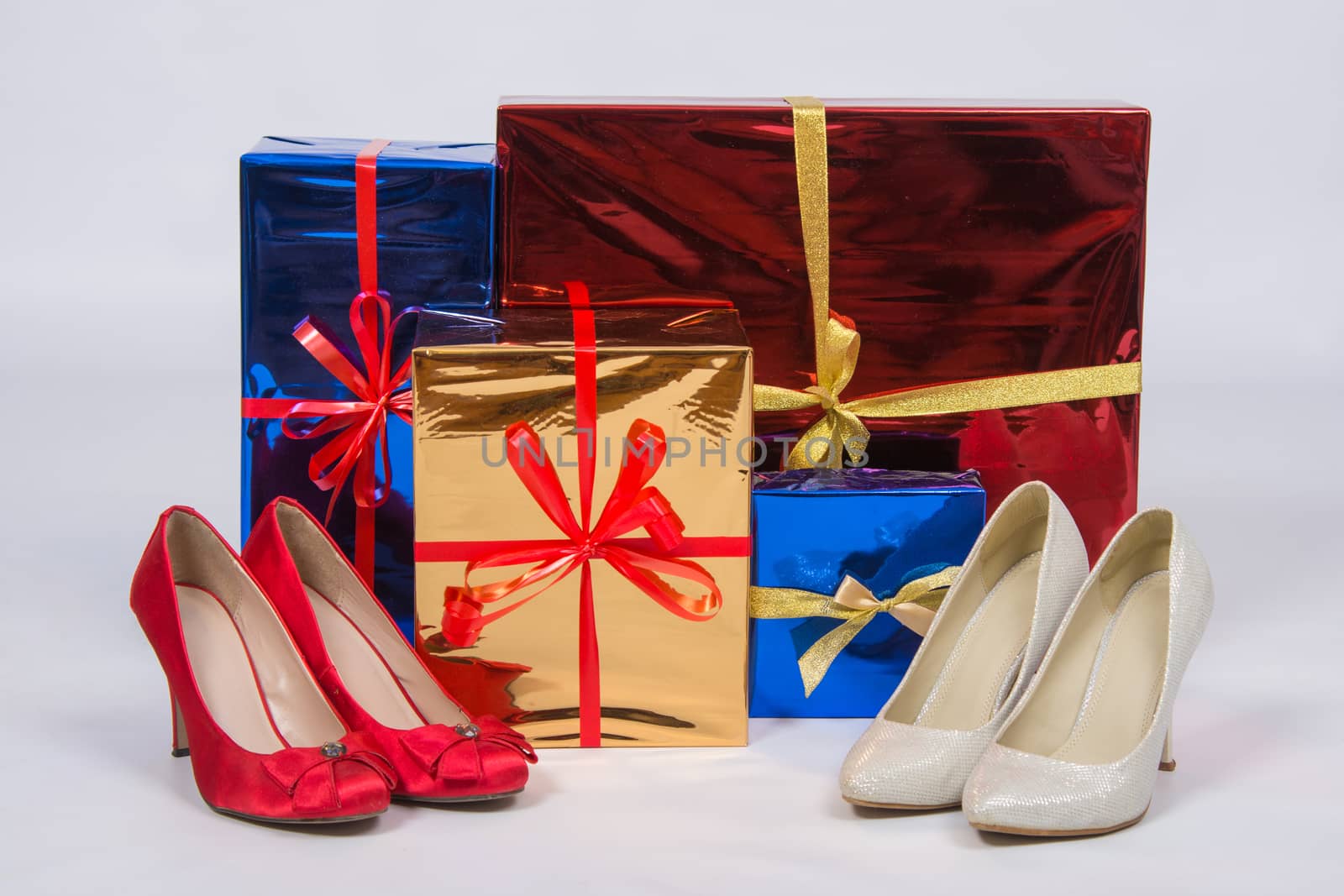 Red and white female shoes with high heels, standing near boxes with gifts