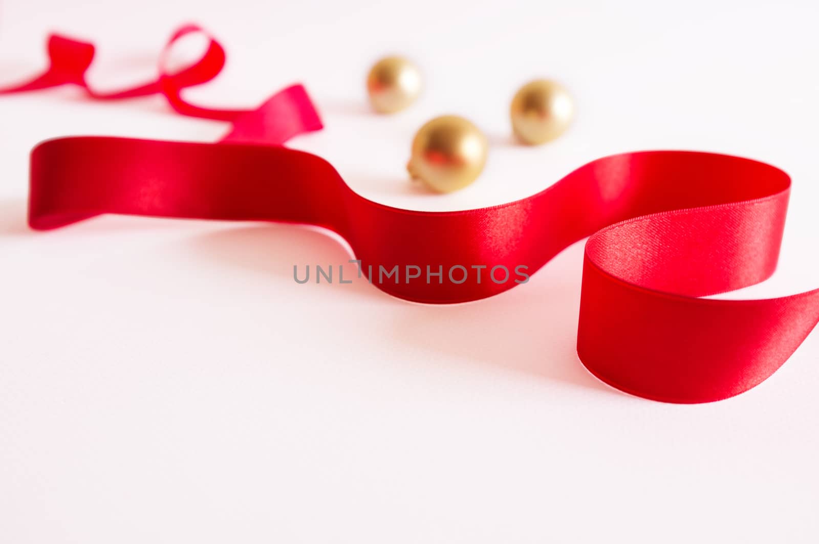 Golden christmas balls with red ribbon on white background.