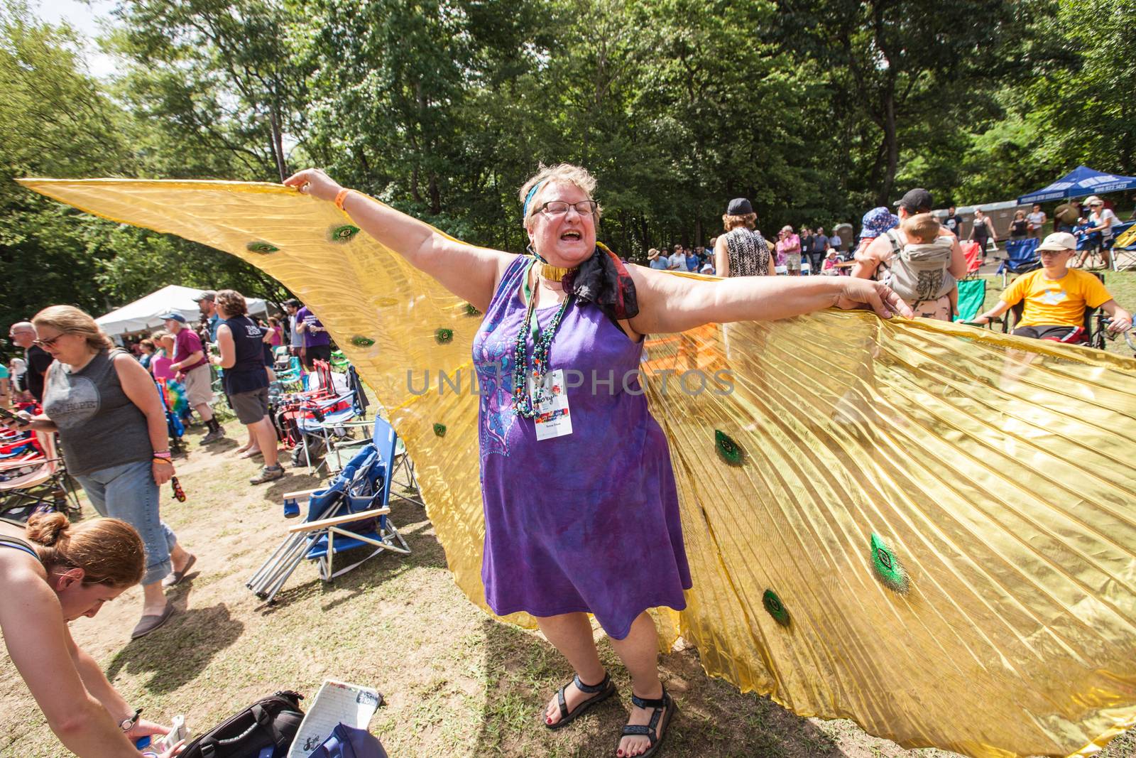 HOT SPRINGS, NC - JULY 10: Happy mature woman in purple dress flying with angel wings at the Wild Goose Festival on July 10, 2016 in Hot Springs, NC, USA.